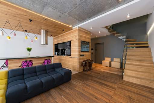 A living room with a blue couch and wooden stairs.