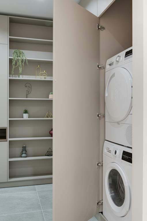 A white washing machine is in a cabinet with shelves.