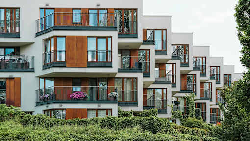 A row of modern townhouses with balconies and flower pots.