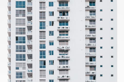 A series of white buildings with balconies and air conditioning units.
