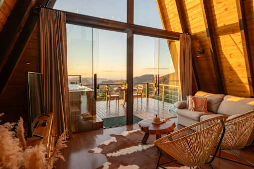 the living room of a cabin with large windows and a couch