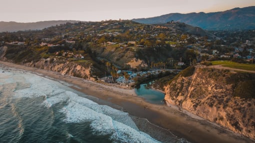 arial view of a beach with houses on the cliffs