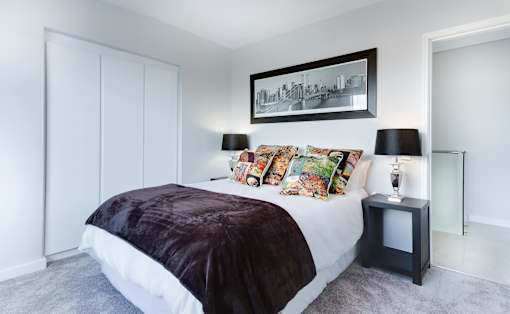A bedroom with a large bed and a picture frame on the wall.