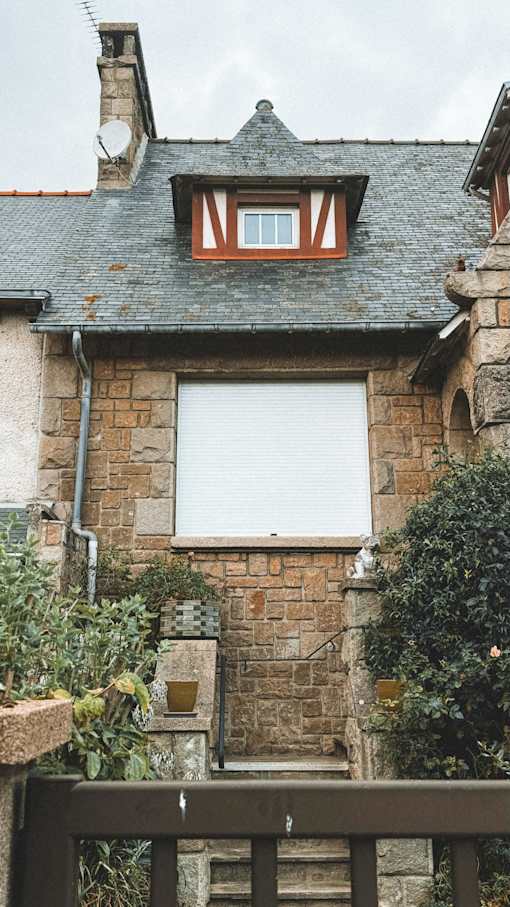 A house with a white window and a brown wooden fence.