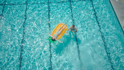 A person swimming in a pool with a yellow floatation device.