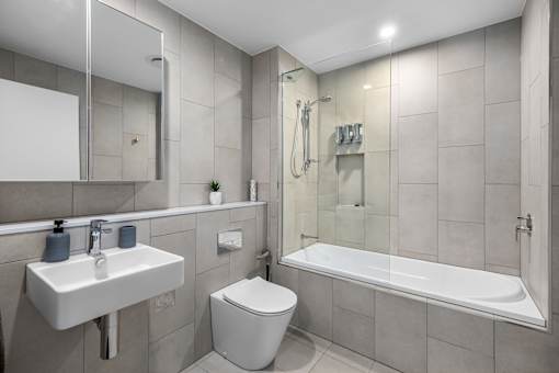A modern bathroom with a white sink, toilet, and bathtub.