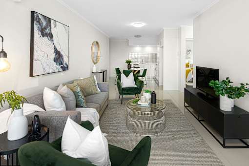 A living room with a grey couch, green chairs, and a coffee table.