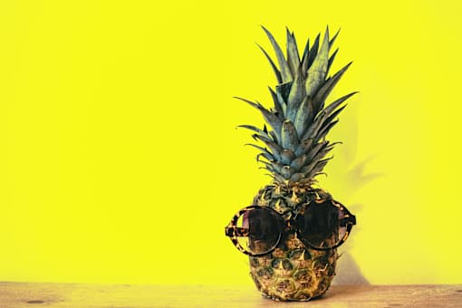 a pineapple wearing sunglasses on a wooden table