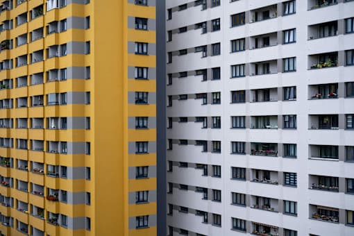 A tall building with a yellow facade stands next to a white building with balconies.