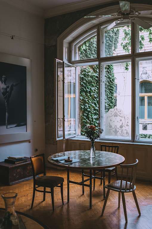 a table and chairs in a room with a large window and a painting on the wall