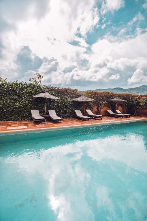 a swimming pool with lounge chairs and umbrellas next to a pool of water