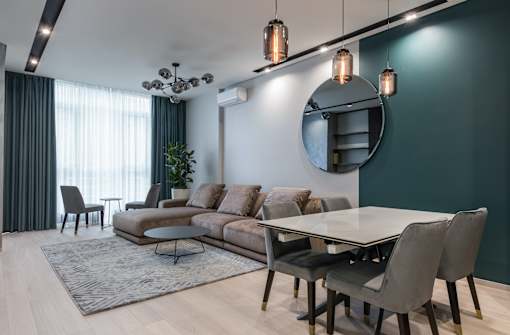 a dark green accent wall in a living room with a brown couch and a white dining table