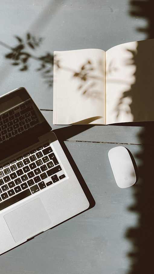 a laptop and mouse on a table with an open book
