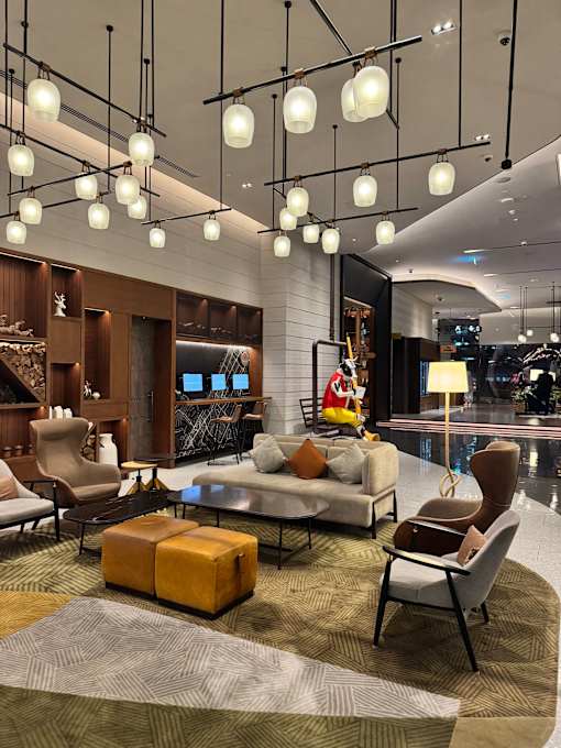 A modern living room with a grey sofa, a brown armchair, a wooden coffee table, and a rug.