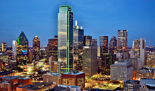 A cityscape at night with a tall green building in the center.
