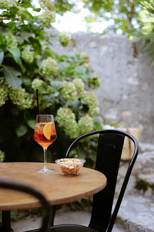 A glass of wine sits on a table with a bowl of nuts.