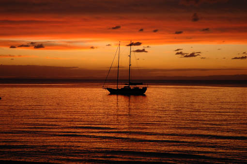 a sailboat in the ocean at sunset