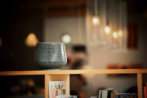 A small speaker is on a shelf with books.