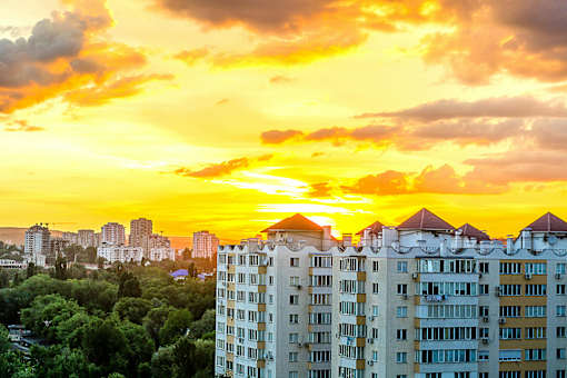 A cityscape with buildings and trees under a sunset sky.