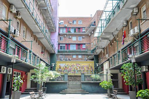 A courtyard with a mural on the wall and a staircase leading to a building.