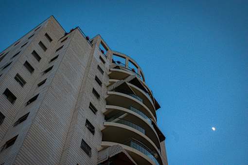 a tall building with balconies and the moon in the background