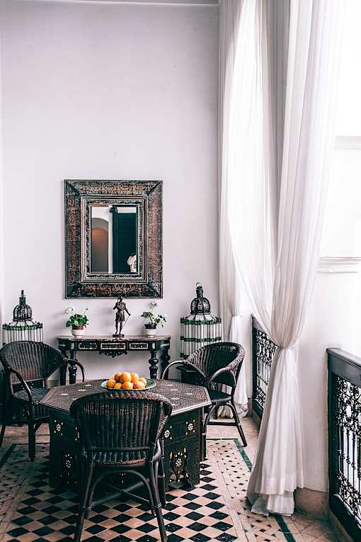 A table with chairs and a mirror on the wall.