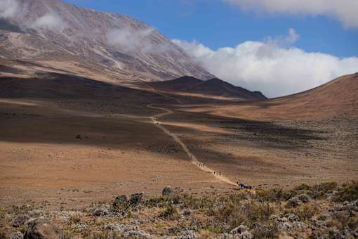 A group of people walking on a trail in a mountainous area.