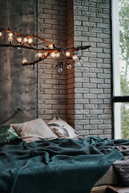 a bed with a green blanket and a christmas tree with lights on it