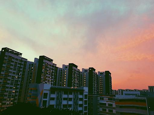 a row of tall buildings at sunset with a colorful sky