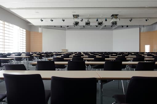 A conference room with rows of tables and chairs.