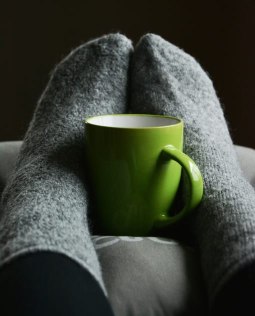 a green coffee cup sitting on top of a gray blanket