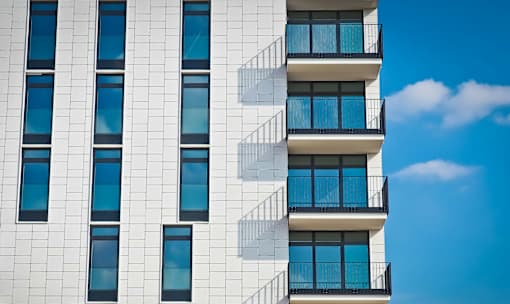 A tall white building with black railings and blue sky in the background.