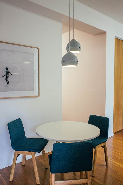 a round table with three blue chairs and a painting on the wall