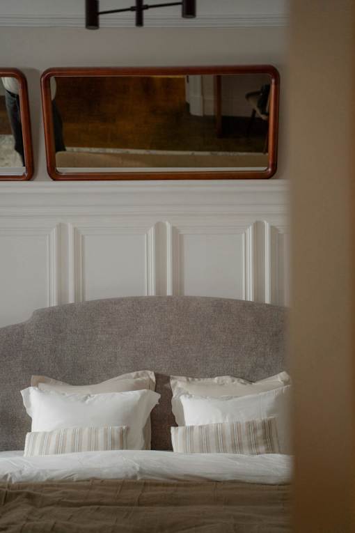A bed with white pillows and a grey headboard.