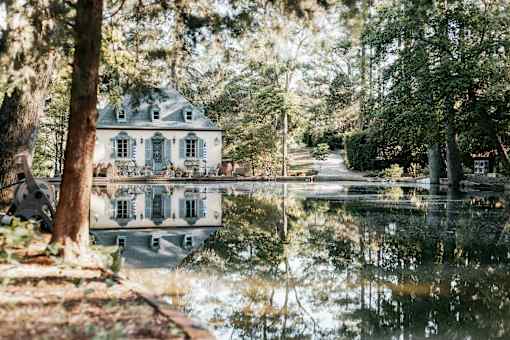 A house is reflected in the water of a pond.