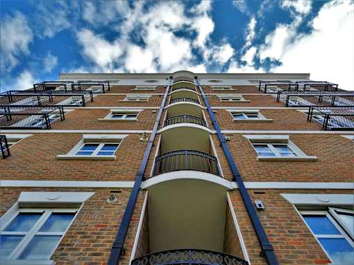 A tall brick building with balconies and windows.