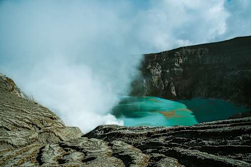 A turquoise pool of water is surrounded by rocky cliffs.