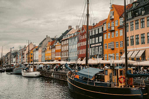 A boat is docked in a harbor with colorful buildings in the background.