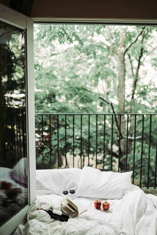 A bed with a book, glasses, and a candle on it.
