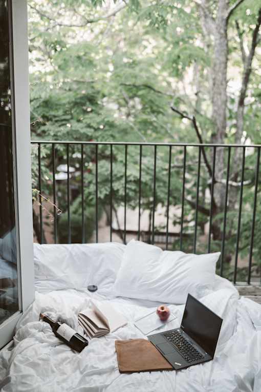 a bed with white sheets and a laptop on it