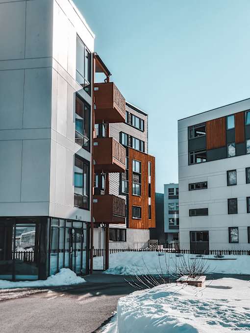 A modern building with a white facade and a brown balcony.