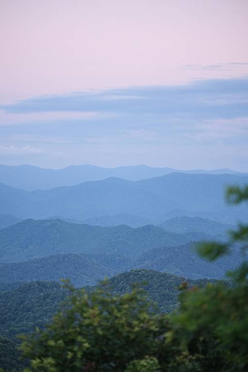 A mountain range covered in greenery under a hazy sky.