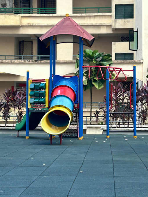 A playground with a blue and yellow slide and a red and blue structure.