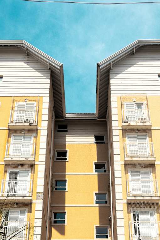 Two buildings with yellow and white facades and balconies.