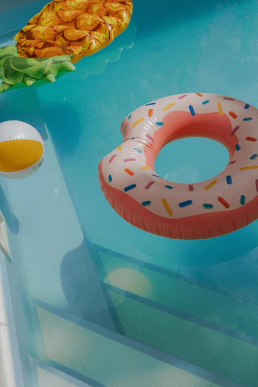 A pineapple and a donut float in a pool.