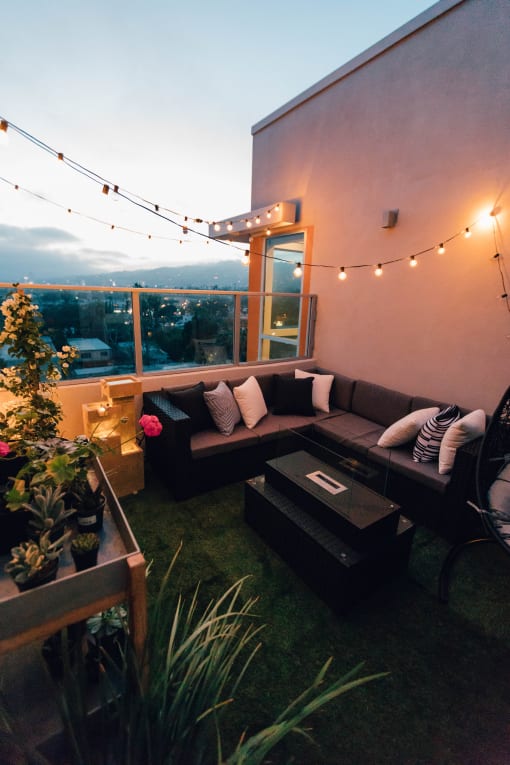 a roof terrace with a sectional sofa and string lights