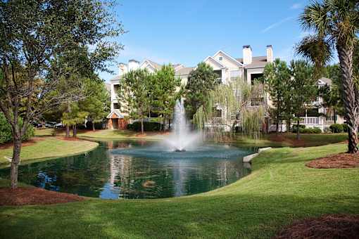a fountain in the middle of a pond in front of a building