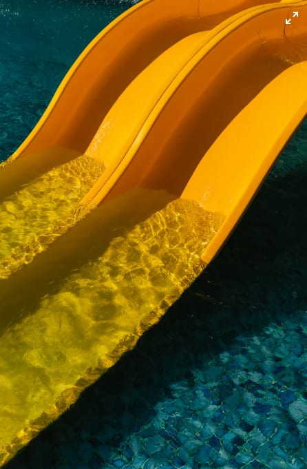 A yellow water slide in a pool.