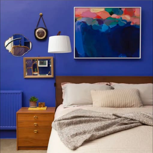 a bedroom with blue walls and a bed with a blanket on it