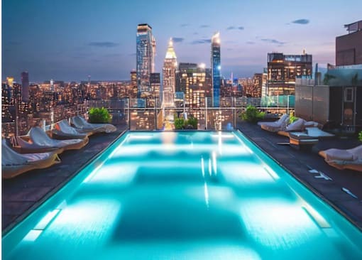a rooftop pool with a view of a city skyline at night